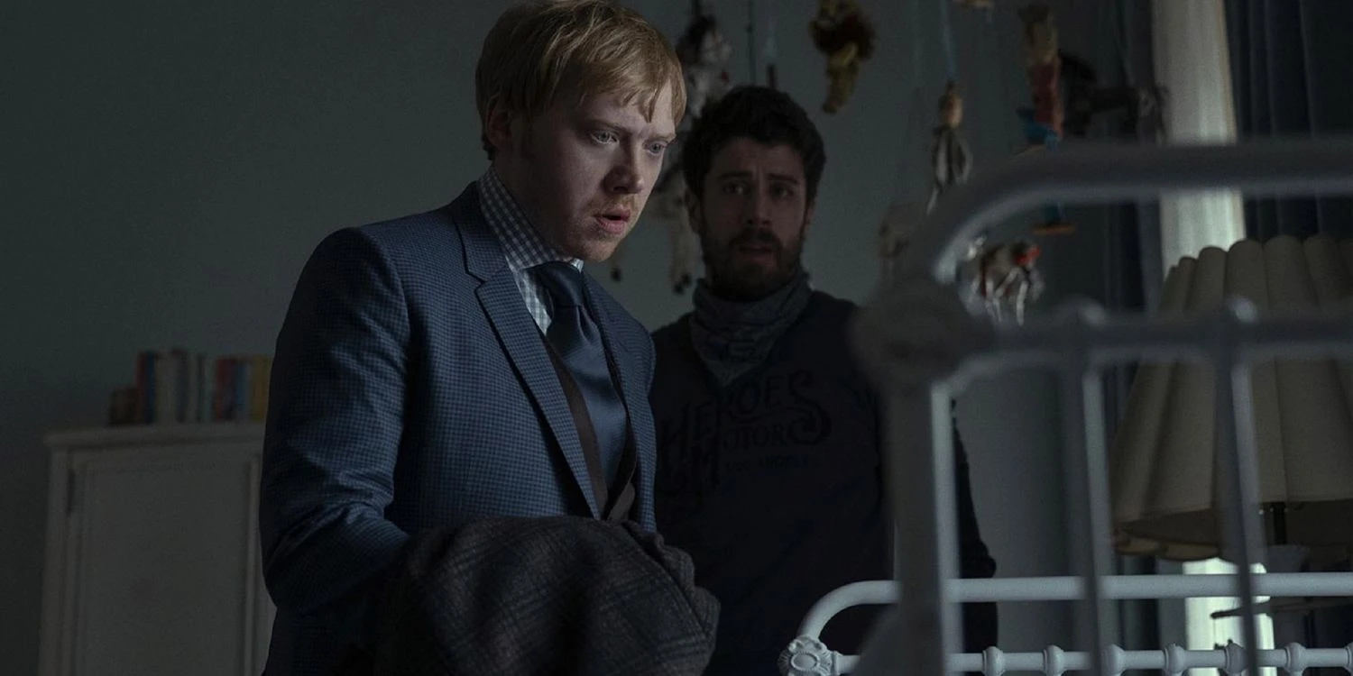 Rupert Grint's character near a cradle in 