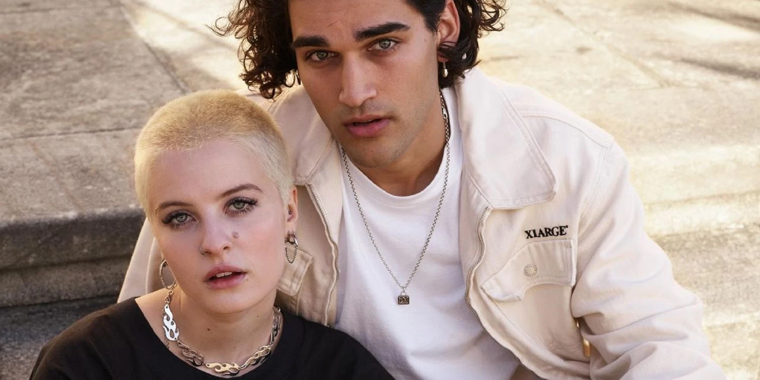 Two characters in 'Heartbreak High' seated on the ground looking at the camera.